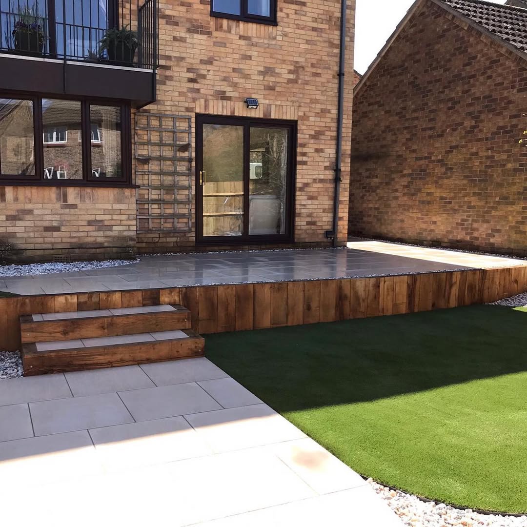 Raised porcelain terrace with sleeper steps and artificial lawn