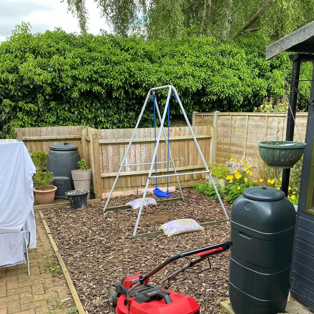 Bare bark-chip rear corner with swing frame before the makeover