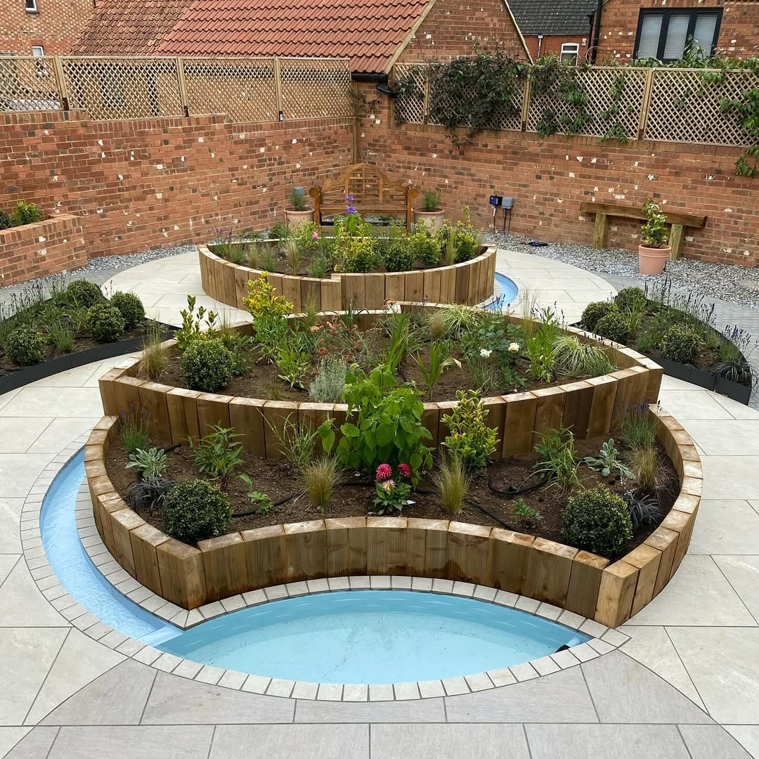 Just-finished courtyard at handover — sleeper tiers freshly planted, before growth